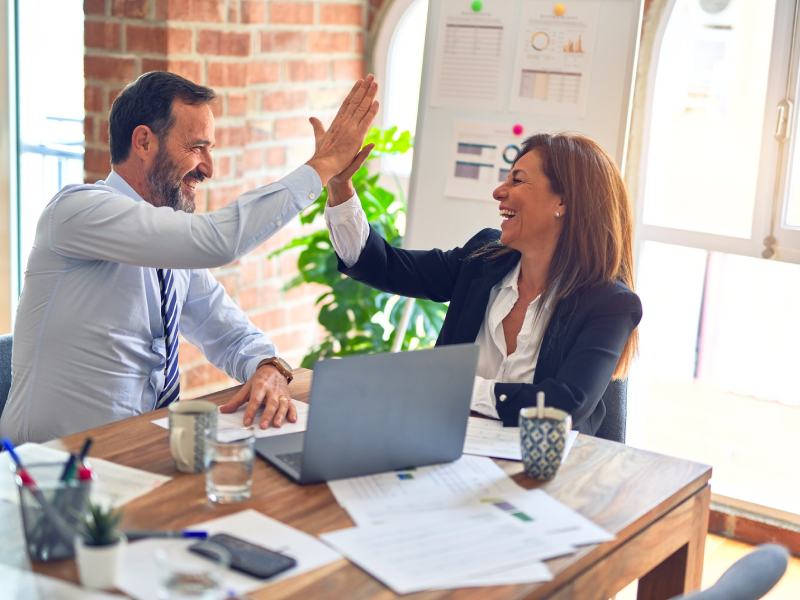 idea01 Man and woman at desk hi-fiving each other